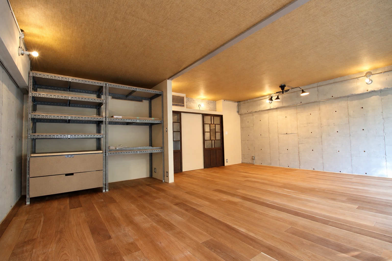 コンクリートの壁と木の床の部屋、格子の引き戸